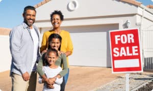 Couple in front of house with For Sale sign they are selling the house by owner FSBO