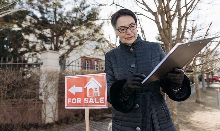 female realtor with house for sale sign